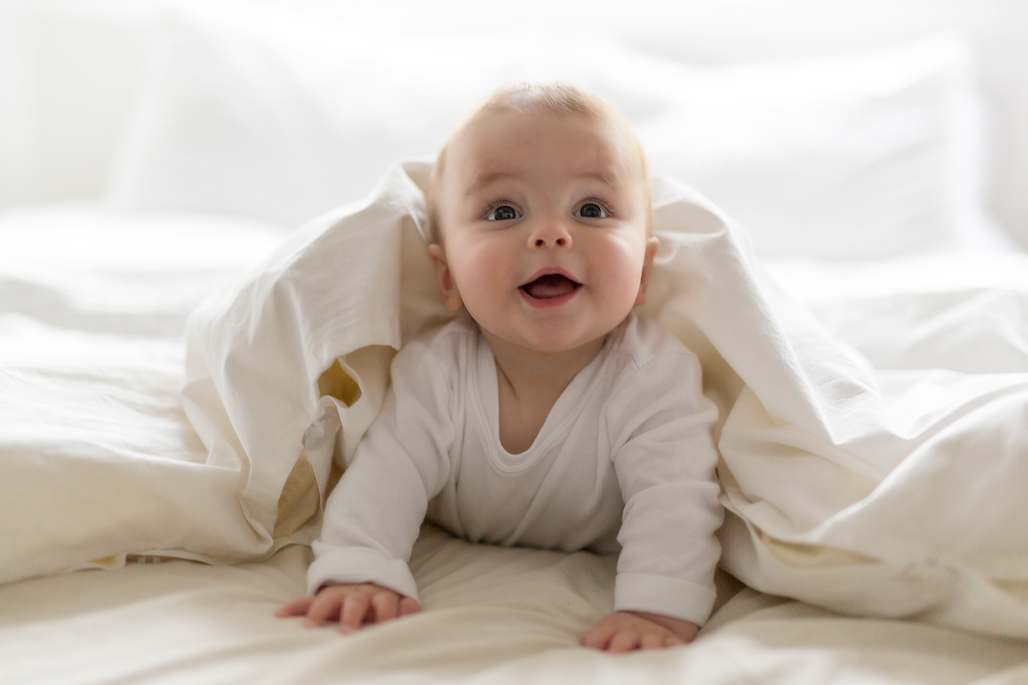 Smiling baby crawling under a blanket