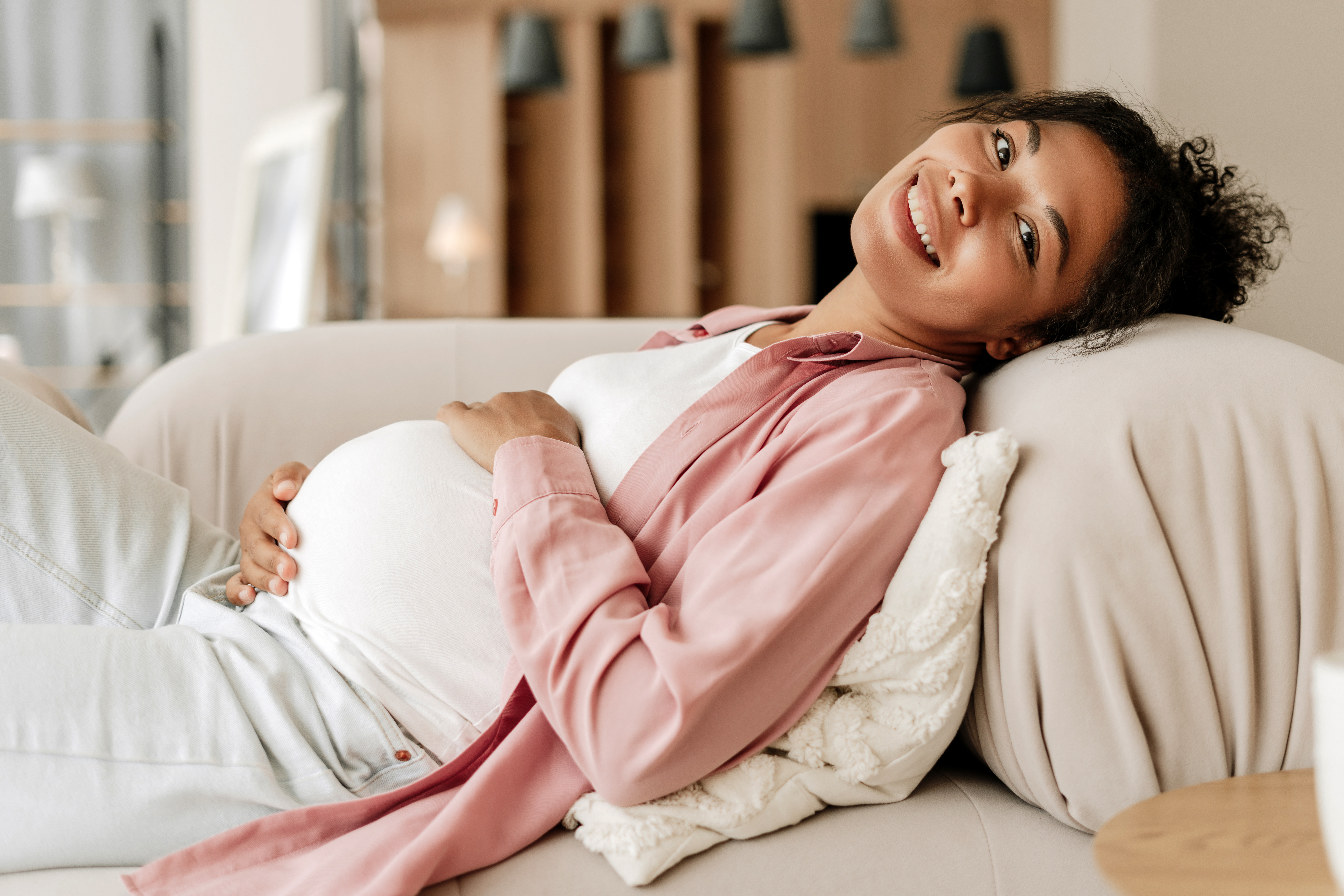 Pregnant person in a striped shirt gently cradling their belly