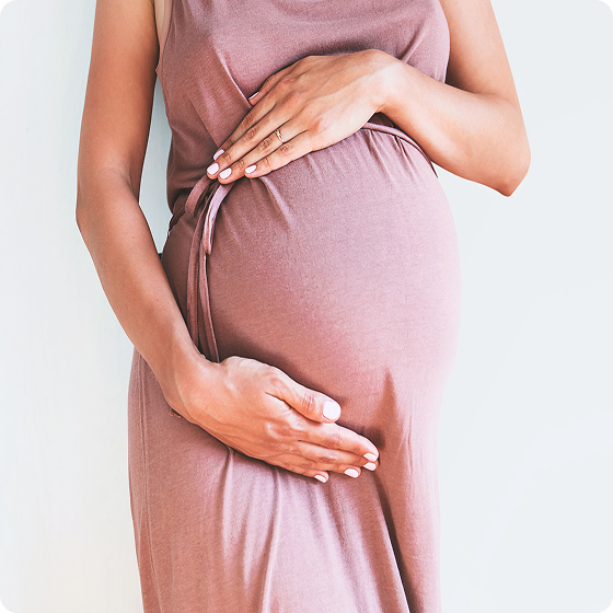Pregnant person in a white shirt holding their belly and smiling