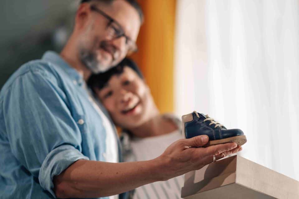 couple holding a baby shoes and thinking about How to Start the Surrogacy Process
